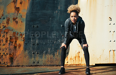 Buy stock photo Shot of a young woman standing with her hands on her knees after a run