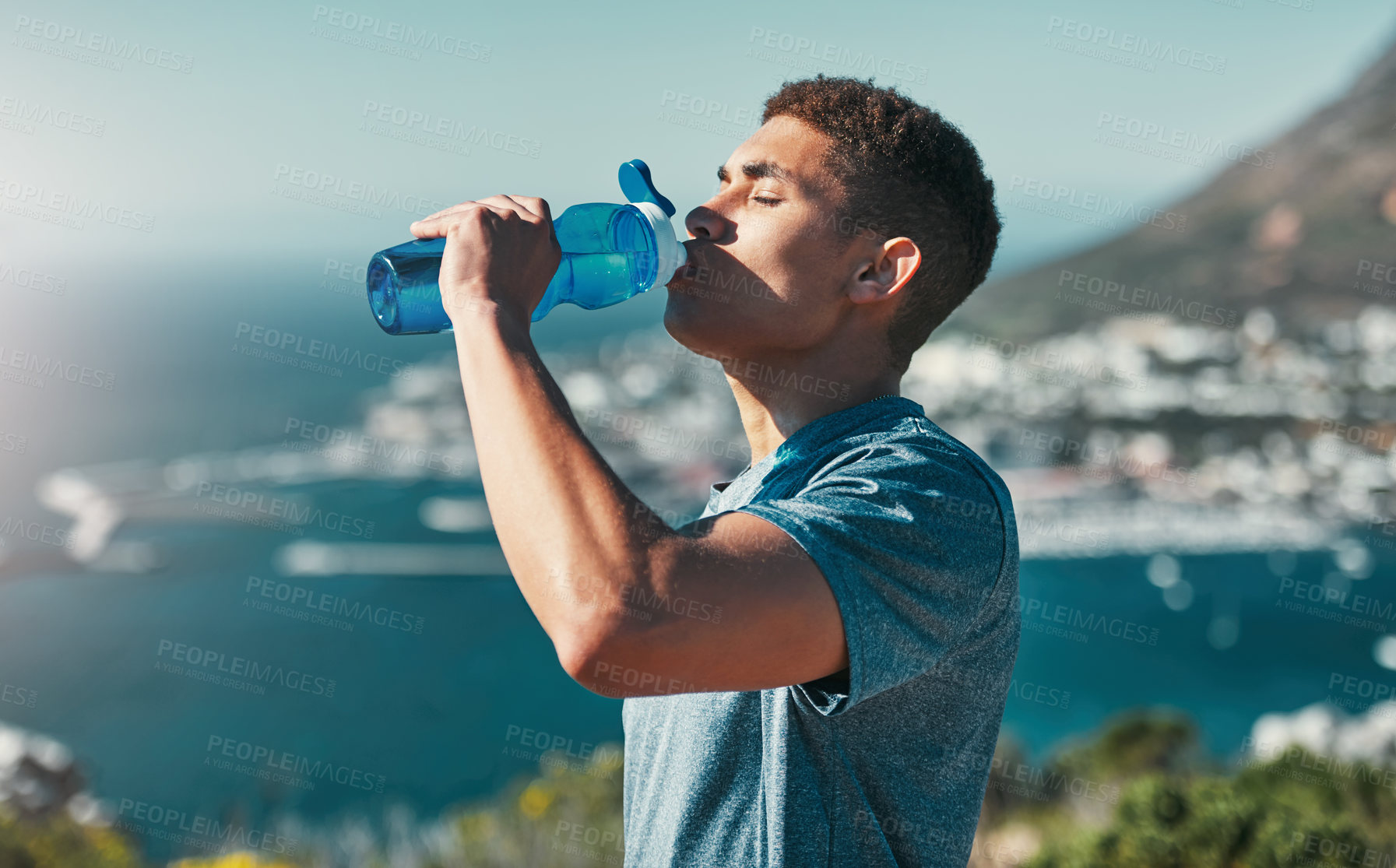 Buy stock photo Cropped shot of a young man drinking water while out for a workout