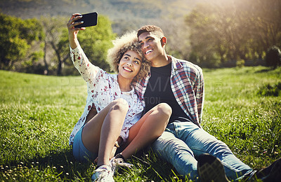 Buy stock photo Shot of a young couple taking a selfie while spending the day at the park