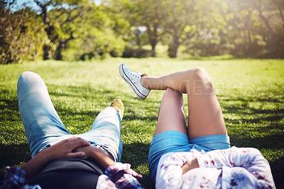 Buy stock photo Cropped shot of a young couple lying on the grass at the park