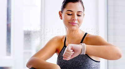Buy stock photo Shot of an attractive young woman checking the time on her wrist watch while working out at the gym