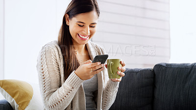 Buy stock photo Shot of an attractive young woman drinking coffee and using a cellphone in her living room at home