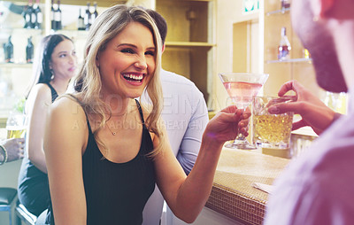 Buy stock photo Shot of a young man and woman toasting with their drinks in a nightclub