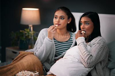 Buy stock photo Popcorn, eating and women or friends with horror movies, scary show and sleepover on bed, streaming service or television. Gen z people relax in bedroom for drama TV film, home cinema or subscription