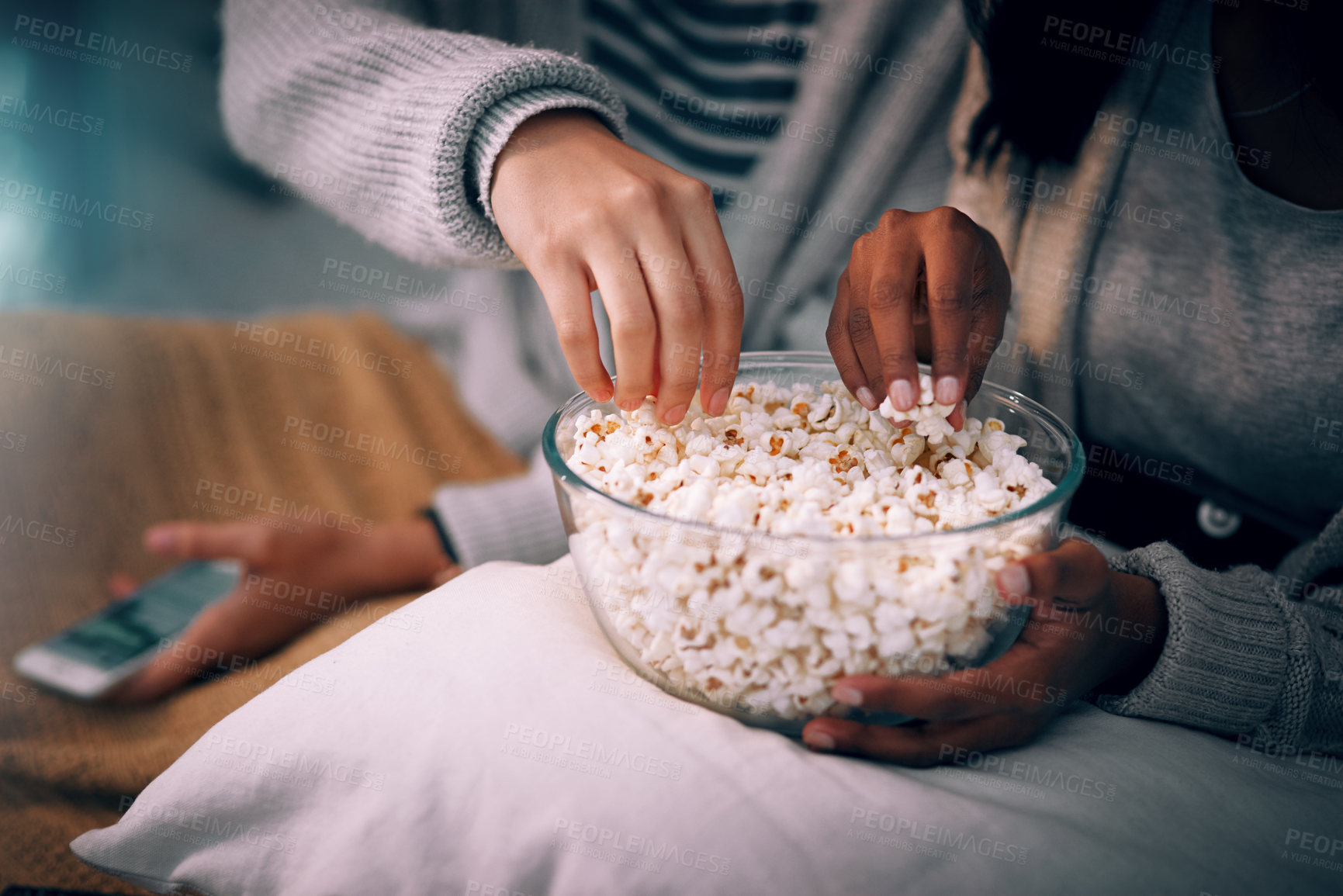 Buy stock photo Hands, friends and home at night with popcorn for social visit, bonding and sleepover. People, relationship and support with smartphone for streaming service, online networking and entertainment