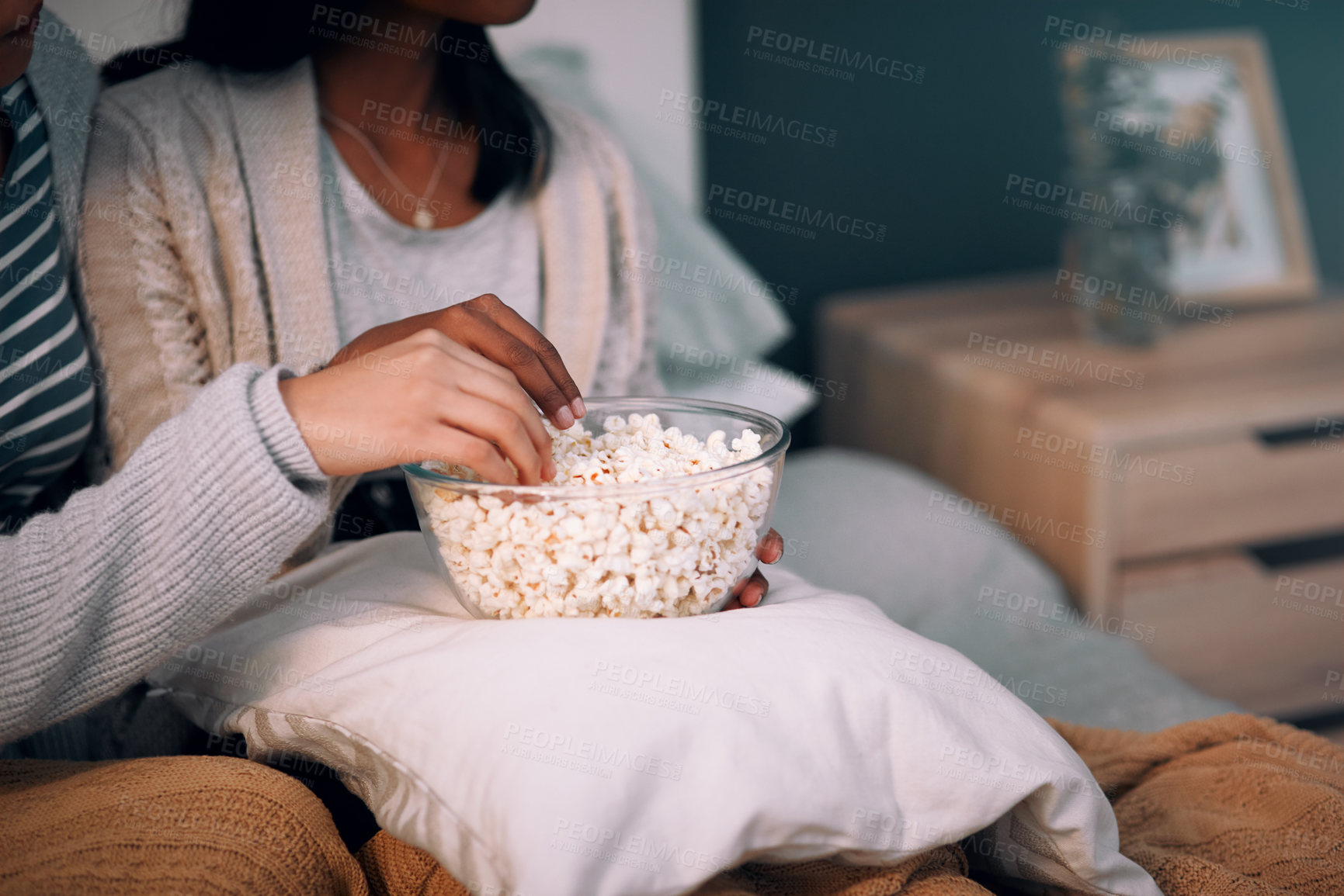 Buy stock photo Cropped shot of two unrecognizable women eating popcorn at home