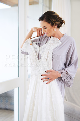 Buy stock photo Cropped shot of a beautiful young bride admiring her wedding dress while preparing for her wedding