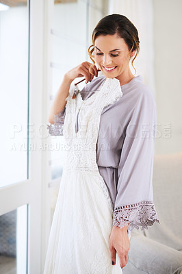 Buy stock photo Cropped shot of a beautiful young bride admiring her wedding dress while preparing for her wedding