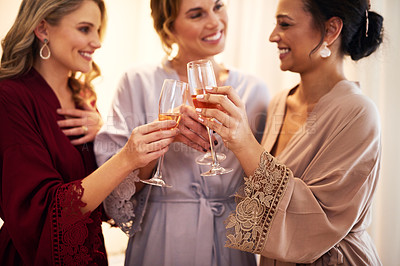 Buy stock photo Cropped shot of a beautiful young bride and her bridesmaids making a toast with wineglasses in their dressing room before the wedding