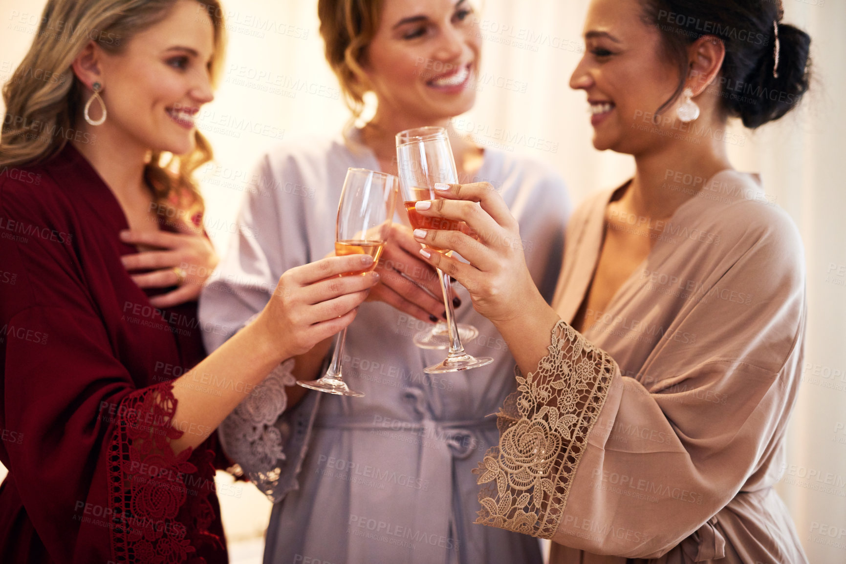 Buy stock photo Cropped shot of a beautiful young bride and her bridesmaids making a toast with wineglasses in their dressing room before the wedding