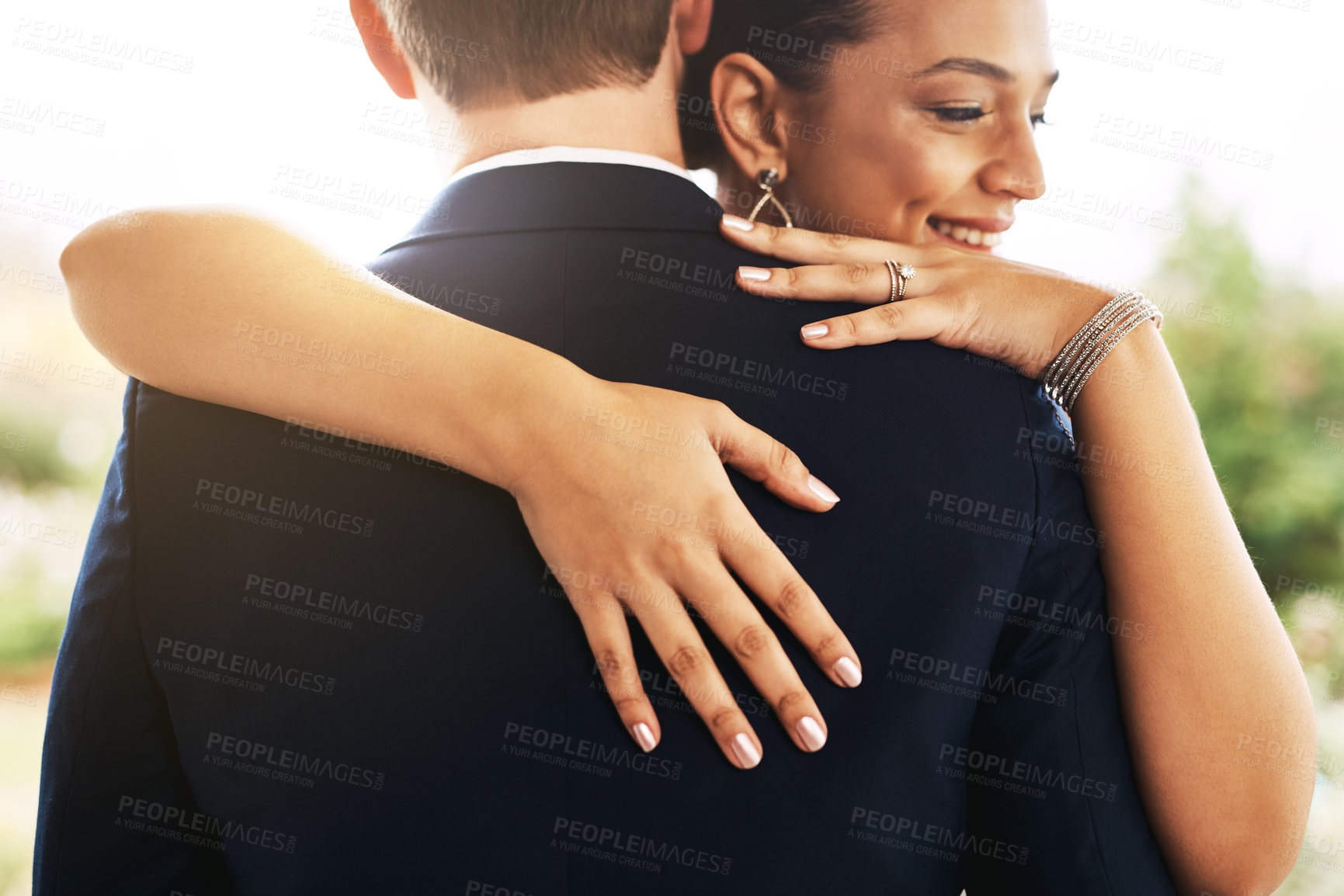 Buy stock photo Shot of a beautiful young bride hugging and embracing her groom outdoors on their wedding day
