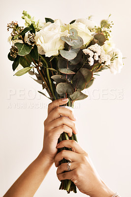Buy stock photo Cropped shot of an unrecognizable bride holding a bouquet of flowers against a light background