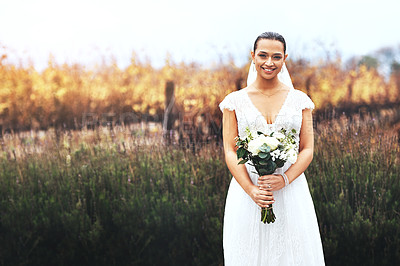 Buy stock photo Portrait of a beautiful young bride holding a bouquet of flowers outdoors on her wedding day