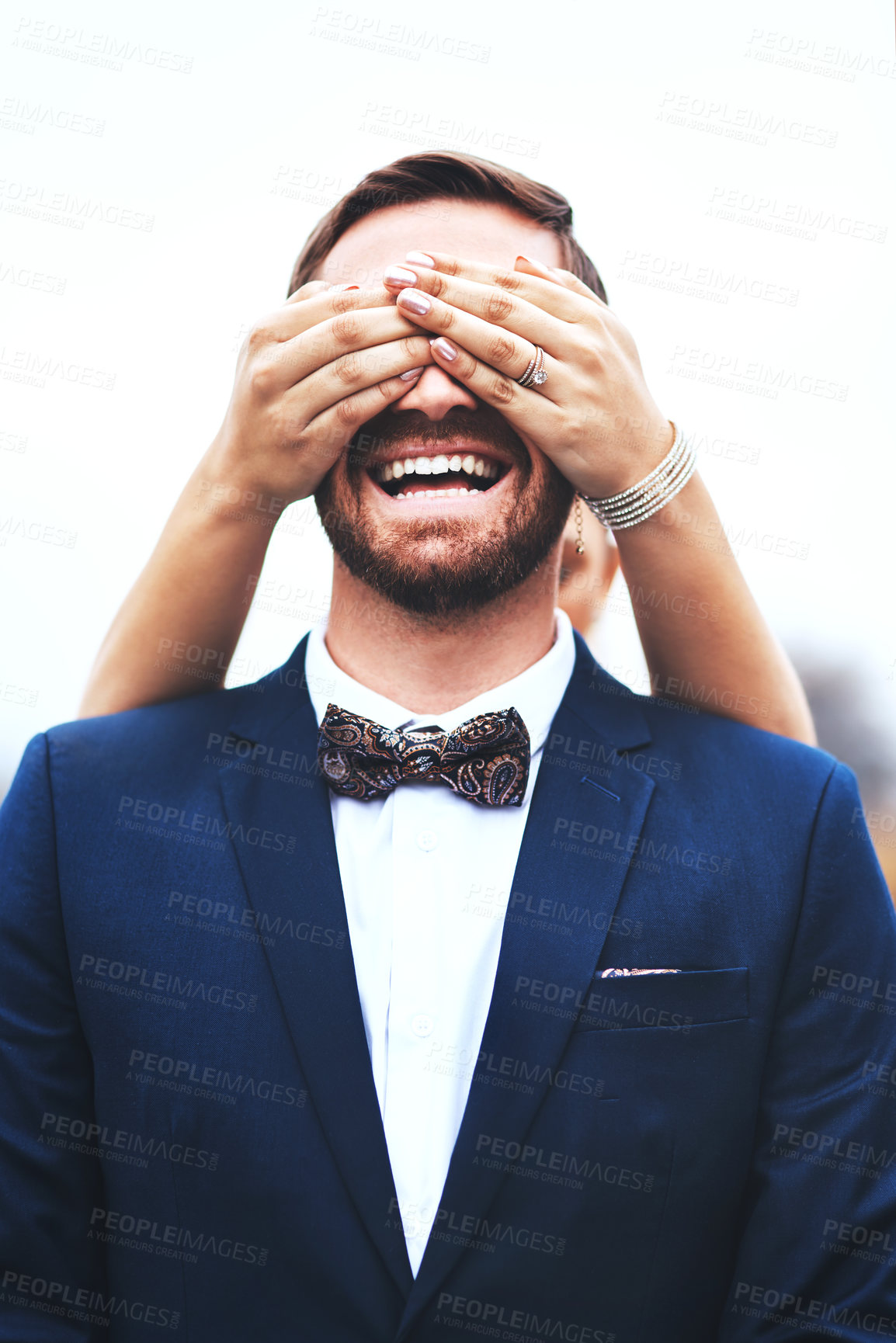 Buy stock photo Shot of a happy bridegroom getting his eyes covered by his bride on their wedding day