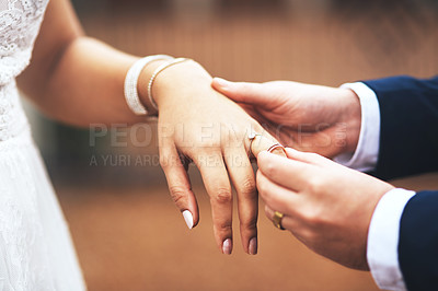 Buy stock photo Cropped shot of an unrecognizable bridegroom putting a ring on his bride's finger on their wedding day