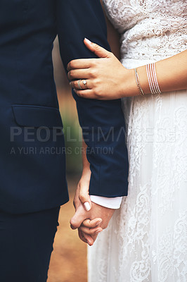 Buy stock photo Cropped shot of an unrecognizable newlywed couple holding hands and walking together on their wedding day