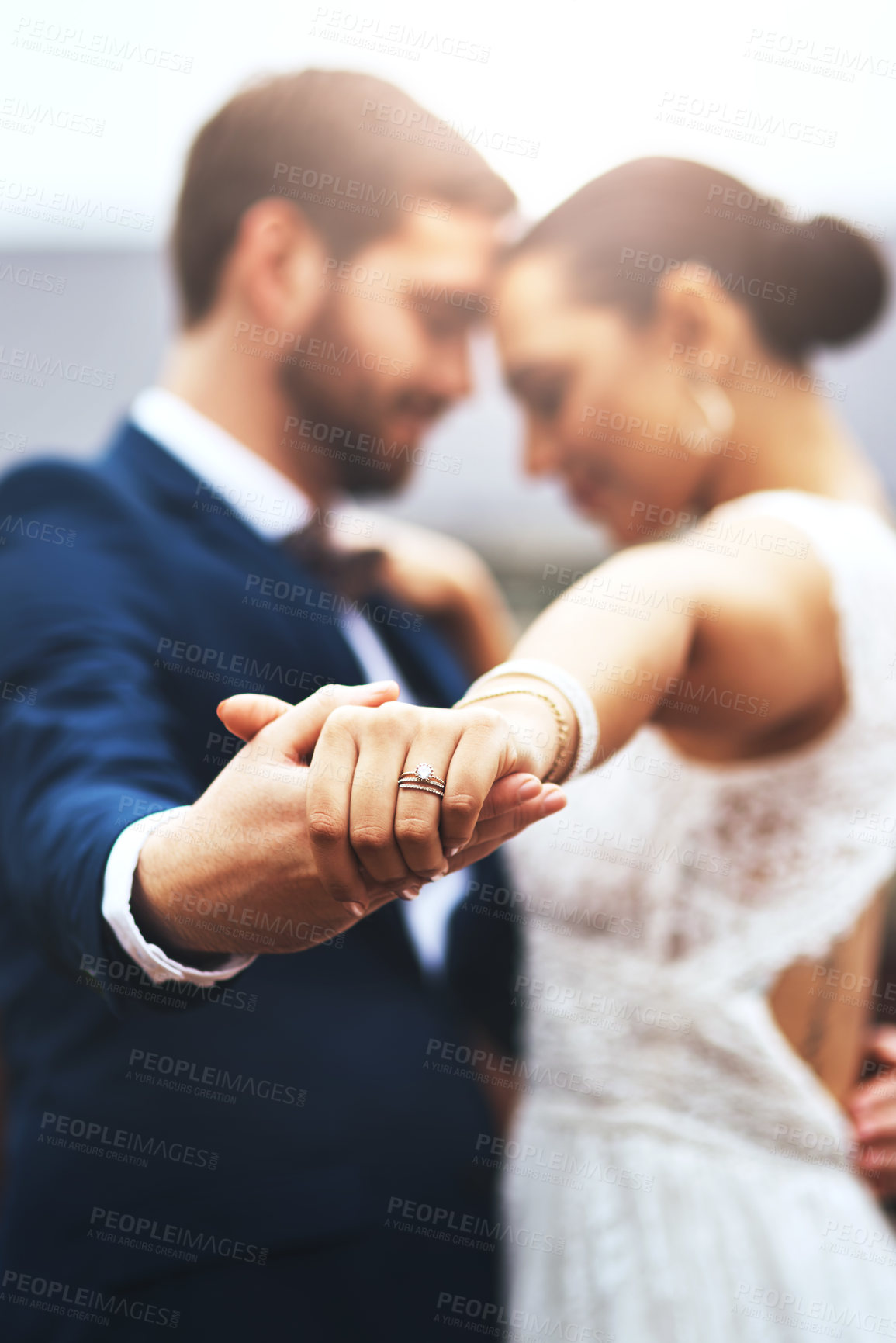 Buy stock photo Shot of a happy newlywed young couple holding hands and dancing together on their wedding day