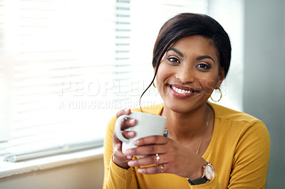 Buy stock photo Cropped shot of an attractive young woman sitting alone and drinking a cup of tea in her home