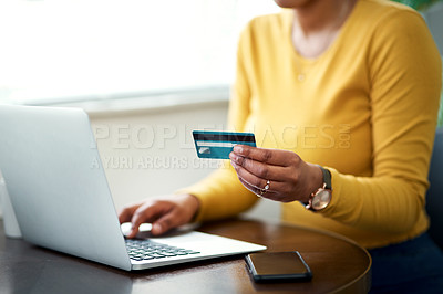 Buy stock photo Cropped shot of an unrecognizable woman sitting alone in her home and using her laptop for online shopping