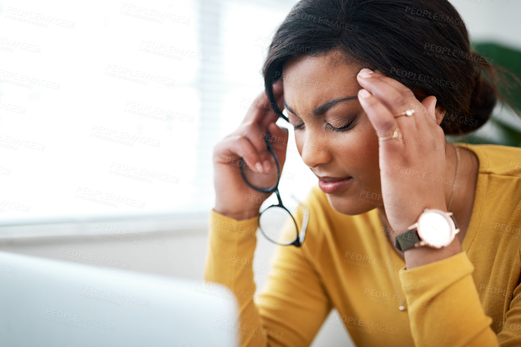 Buy stock photo Cropped shot of an attractive young woman sitting in her home and suffering from a headache while using her laptop