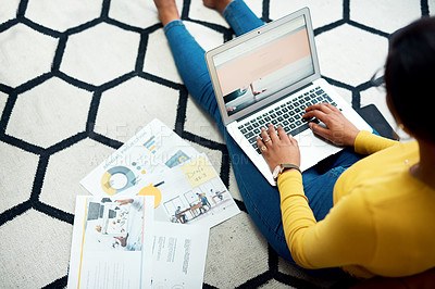 Buy stock photo Cropped shot of an unrecognizable woman sitting on the floor and using her laptop after reading paperwork
