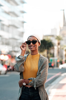 Buy stock photo Cropped shot of an attractive young woman wearing sunglasses and a hijab while standing alone in the city