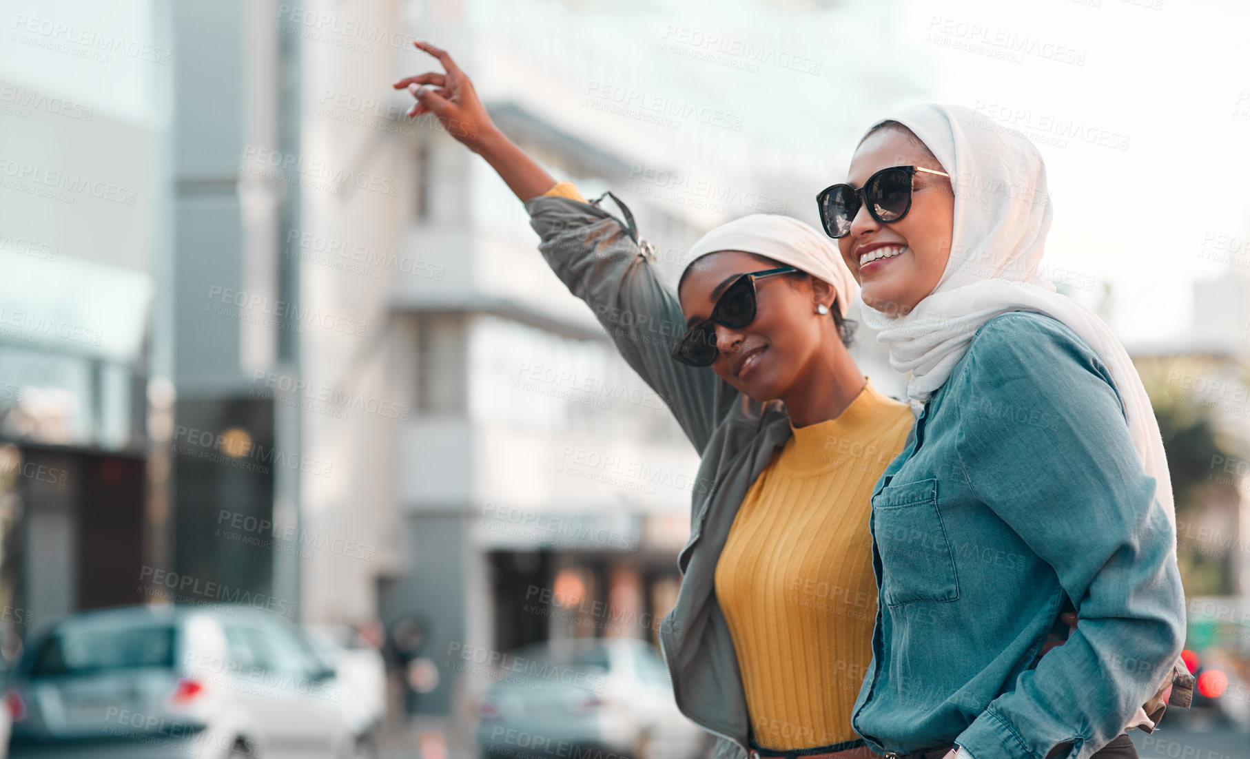 Buy stock photo Cropped shot of two attractive young women wearing sunglasses and headscarves while hailing a taxi in the city