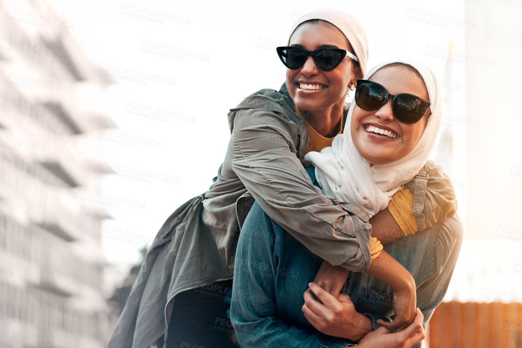 Buy stock photo Muslim woman, friends and piggyback in city with freedom, youth and urban travel together in Qatar. Islamic women, happiness and walking in metro with funny game, sunglasses and comic journey