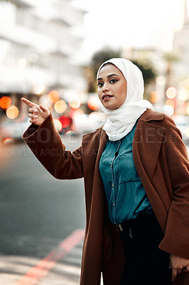 Buy stock photo Cropped shot of an attractive young woman wearing a hijab and hailing a taxi in the city