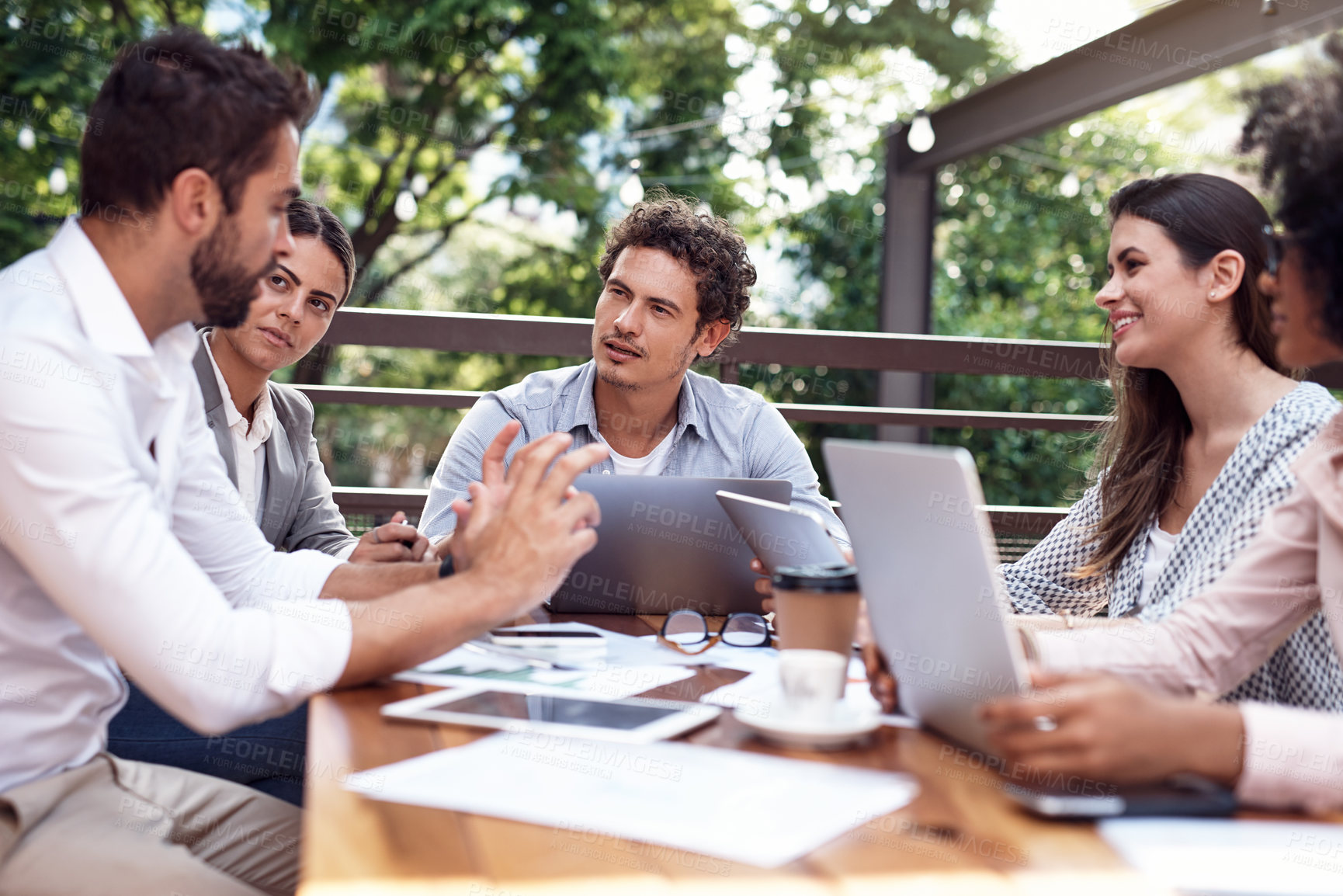 Buy stock photo Cropped shot of a diverse group of businesspeople sitting together and having a meeting outside the office