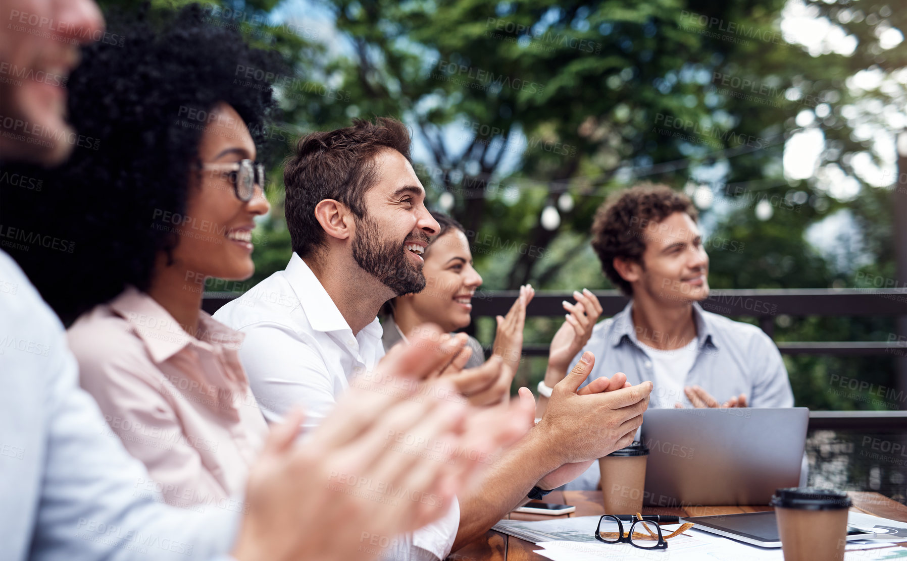 Buy stock photo Cropped shot of a diverse group of businesspeople sitting together and clapping after a successful meeting in outdoors