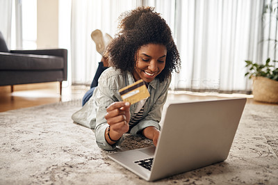 Buy stock photo Shot of a young woman holding her credit card while using her laptop