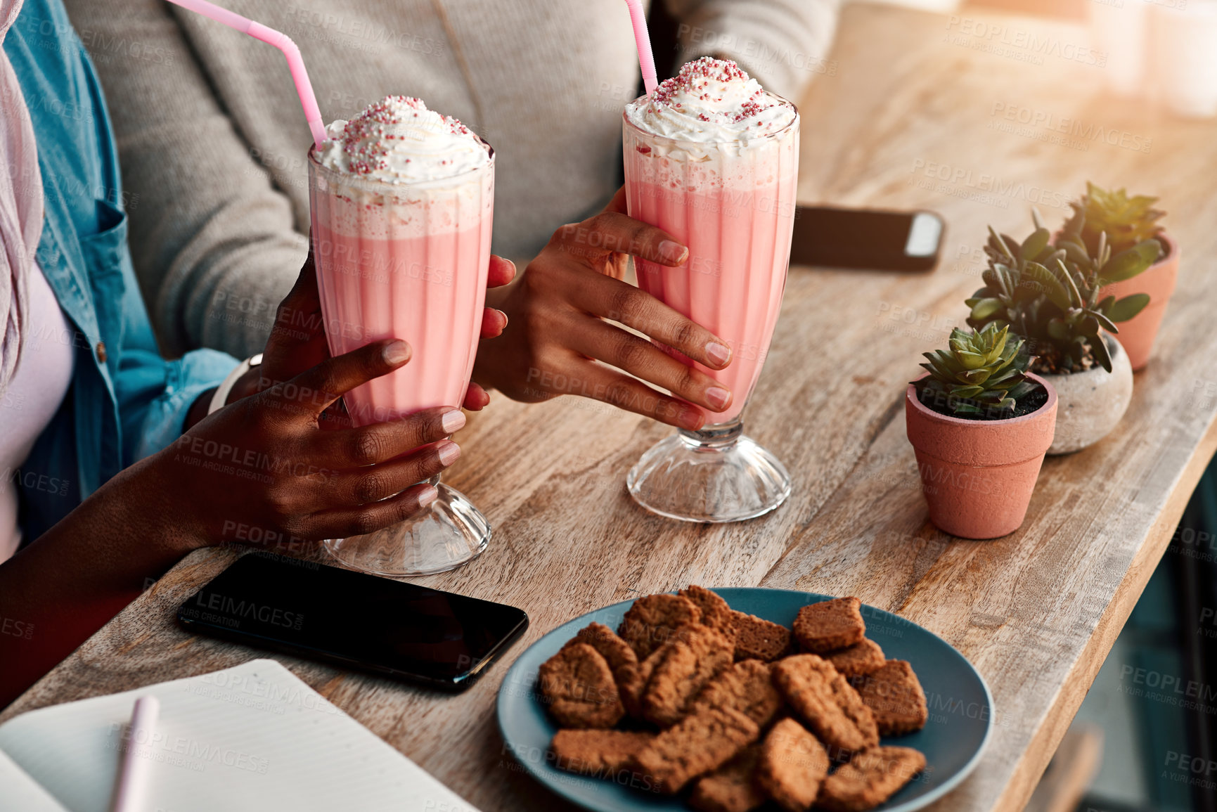 Buy stock photo Cropped shot of an unrecognizable woman having a milkshake and cookies with her friend at a cafe