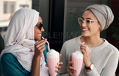 Buy stock photo Cropped shot of two affectionate young girlfriends having milkshakes together in a cafe while dressed in hijab