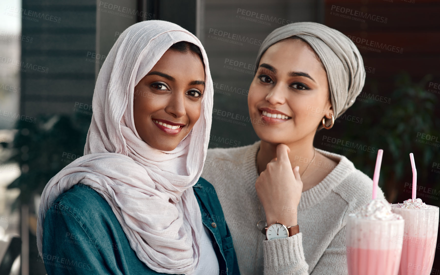 Buy stock photo Cropped portrait of two affectionate young girlfriends hanging out together at a milkshake cafe while dressed in hijab
