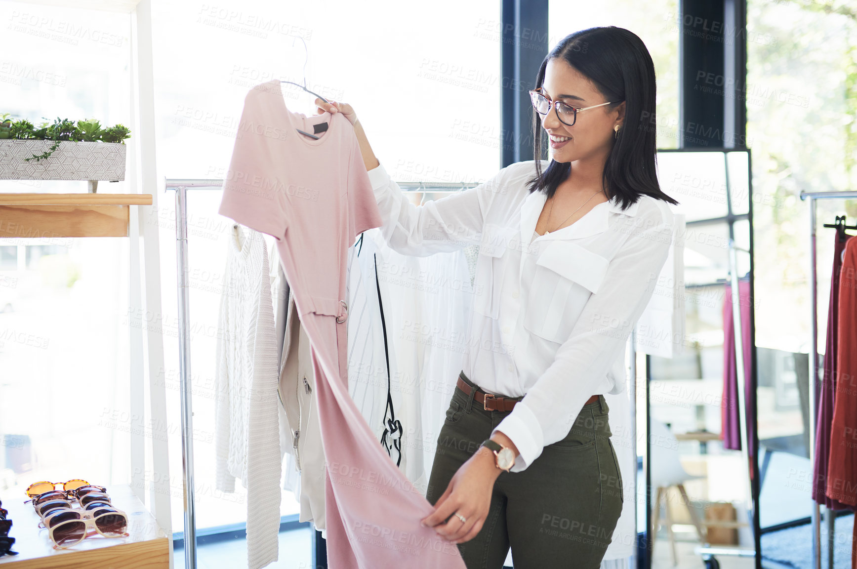 Buy stock photo Shot of a young woman shopping for clothes in a store