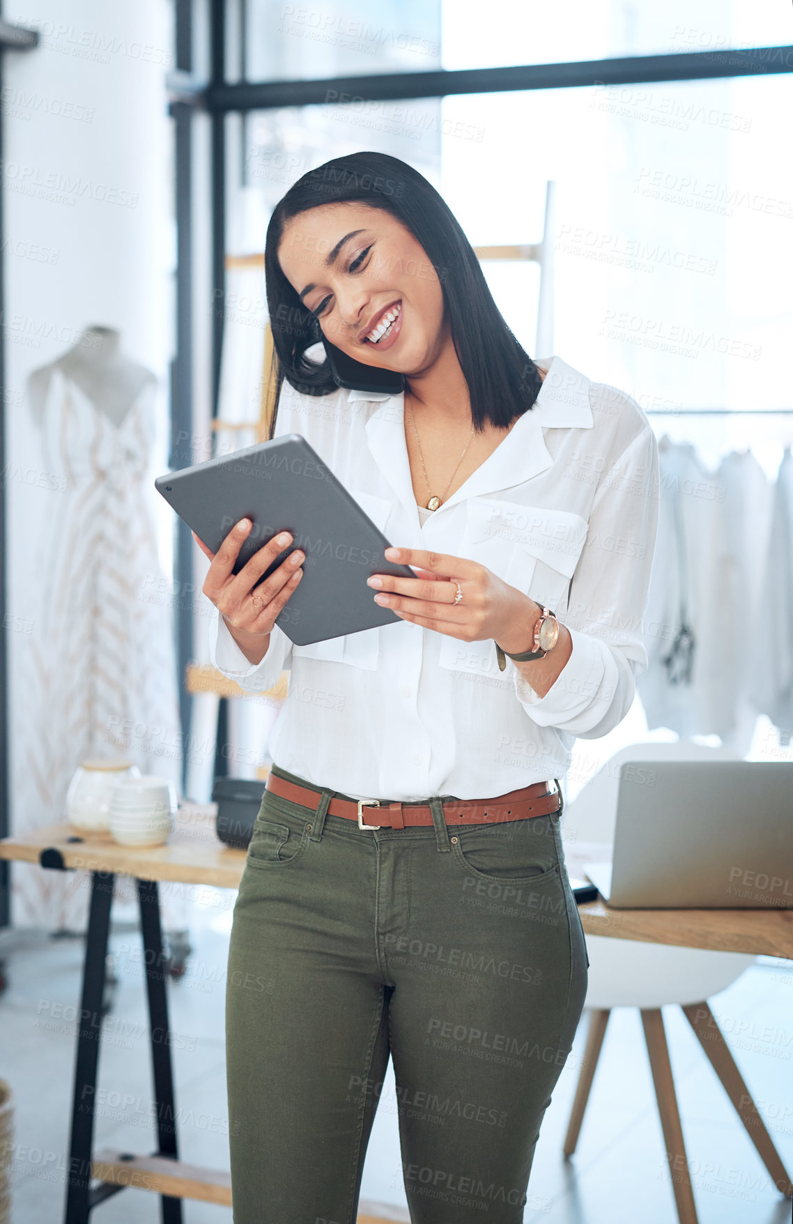 Buy stock photo Shot of a young business owner talking on her cellphone while using a digital tablet in her store