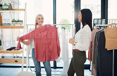 Buy stock photo Shot of a sales assistant helping a young woman in a clothing boutique