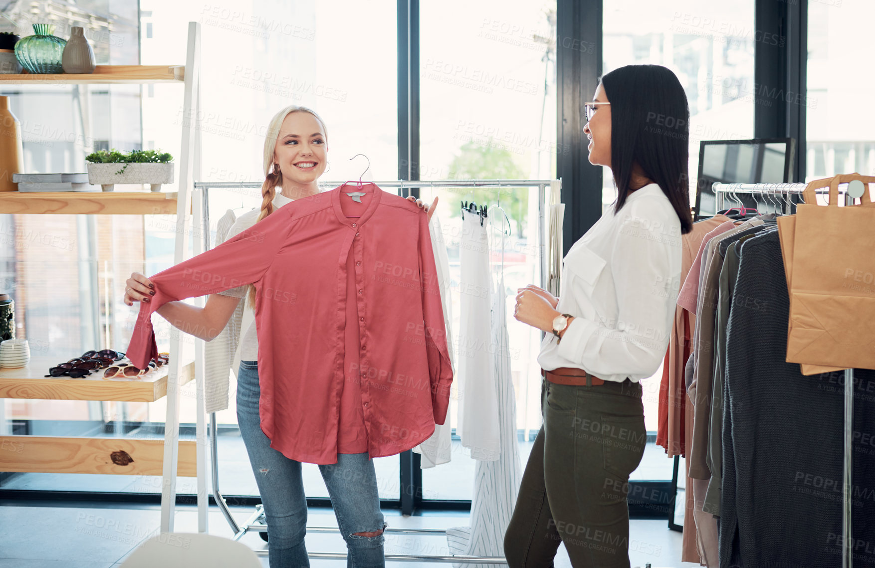 Buy stock photo Shot of a sales assistant helping a young woman in a clothing boutique