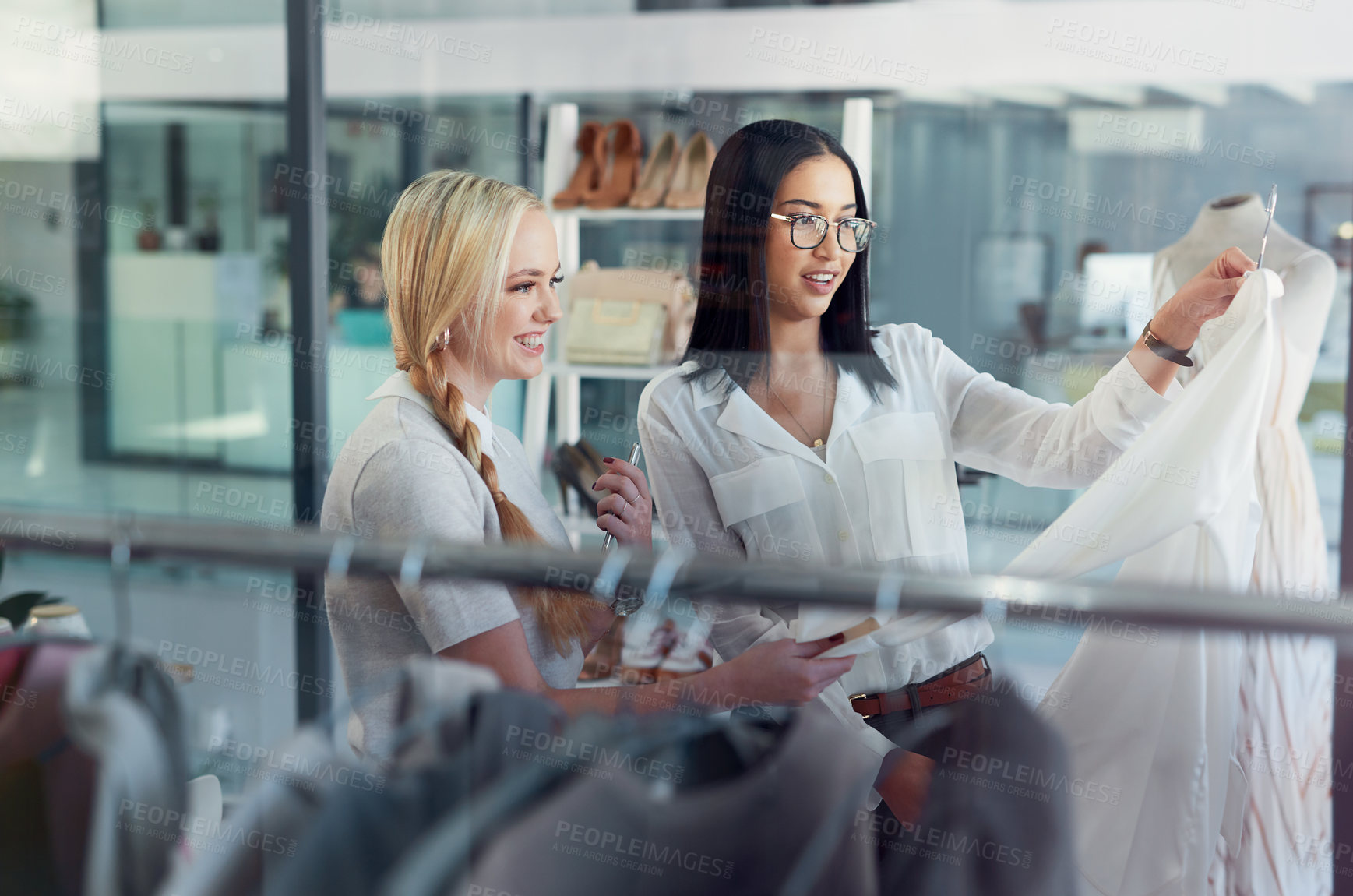 Buy stock photo Shot of a sales assistant helping a young woman in a clothing boutique