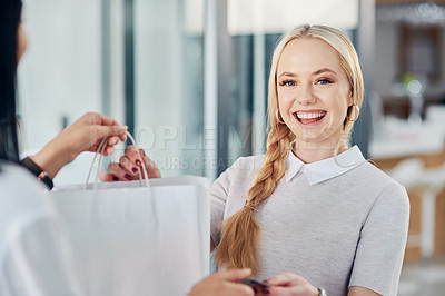Buy stock photo Cropped shot of a young woman making a purchase in a clothing store