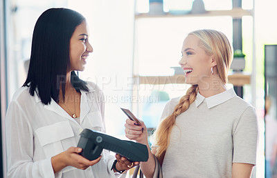Buy stock photo Shot of a young woman paying by card in a clothing store