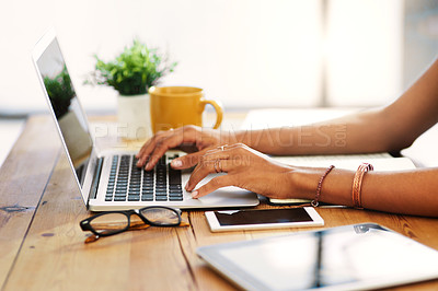 Buy stock photo Cropped shot of an unrecognizable businesswoman sitting alone and typing on her laptop during the day at home