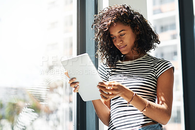 Buy stock photo Cropped shot of an attractive young businesswoman standing alone in her home and using a tablet