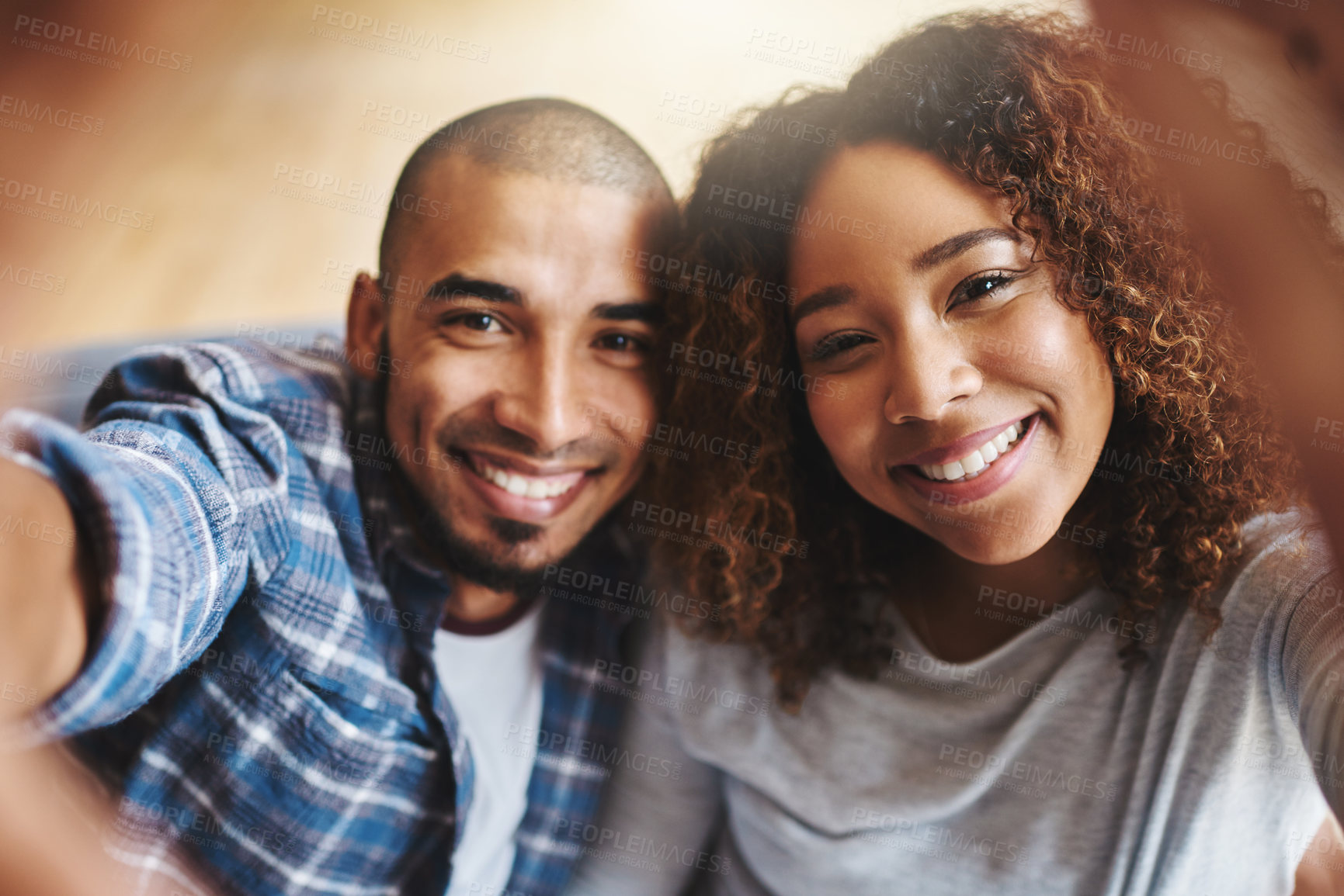 Buy stock photo Cropped portrait of an affectionate young couple sitting on their sofa together and posing for a selfie