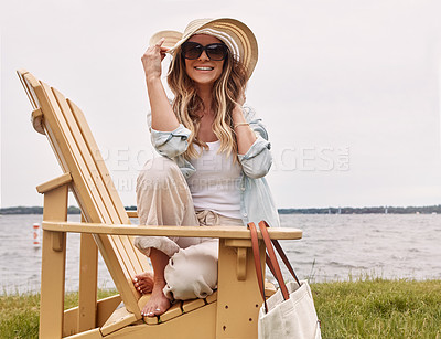 Buy stock photo Shot of a beautiful young woman relaxing on a chair next a lake