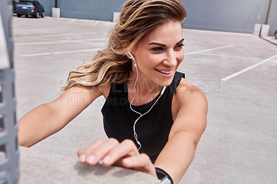 Buy stock photo Shot of a sporty young woman stretching while exercising outdoors