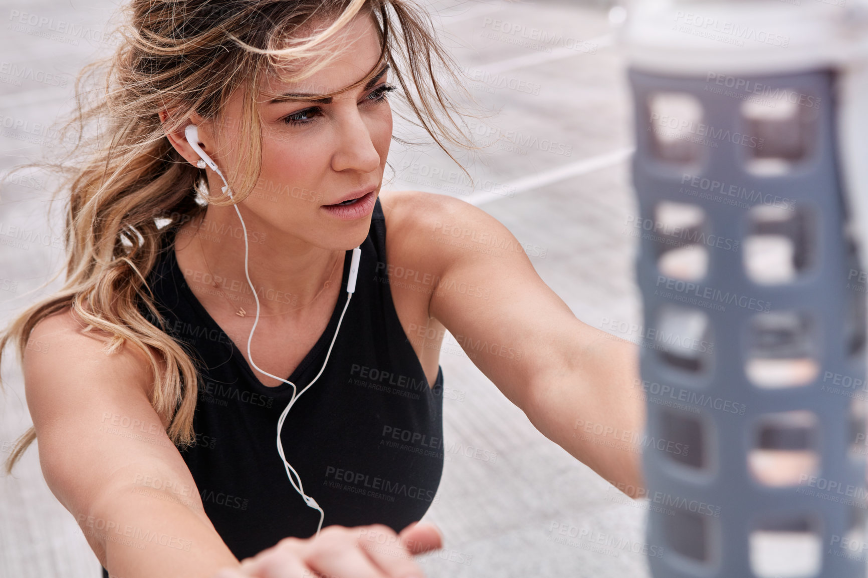 Buy stock photo Shot of a sporty young woman stretching while exercising outdoors