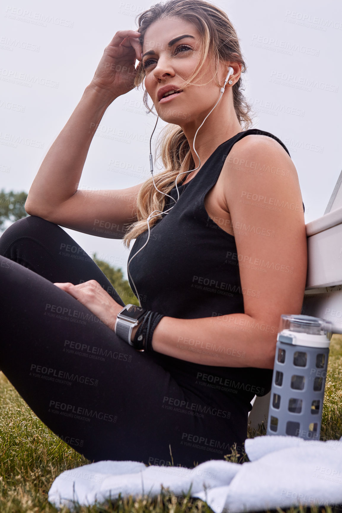 Buy stock photo Shot of a sporty young woman taking a break while exercising outdoors