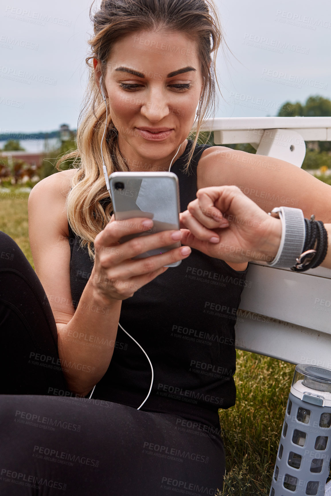 Buy stock photo Shot of a sporty young woman using a cellphone while exercising outdoors